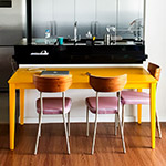 Cozinha com mesa amarela e cadeiras de forro rosa